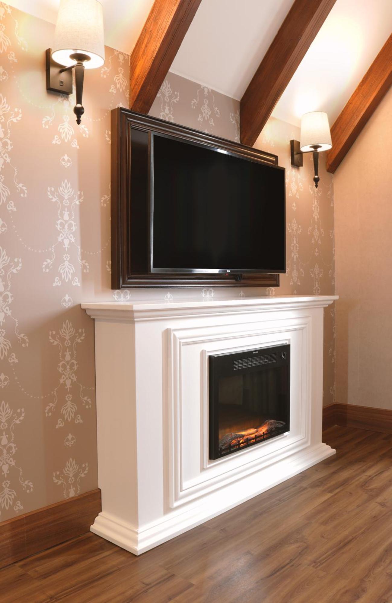 Buona Vitta Gramado Resort & Spa By Gramado Parks Exterior foto The image shows a modern living room setup featuring a white mantel with an electric fireplace. Above the mantel, there is a large flat-screen television mounted on the wall. The fireplace has a glass front and displays a realistic flame effect, crea